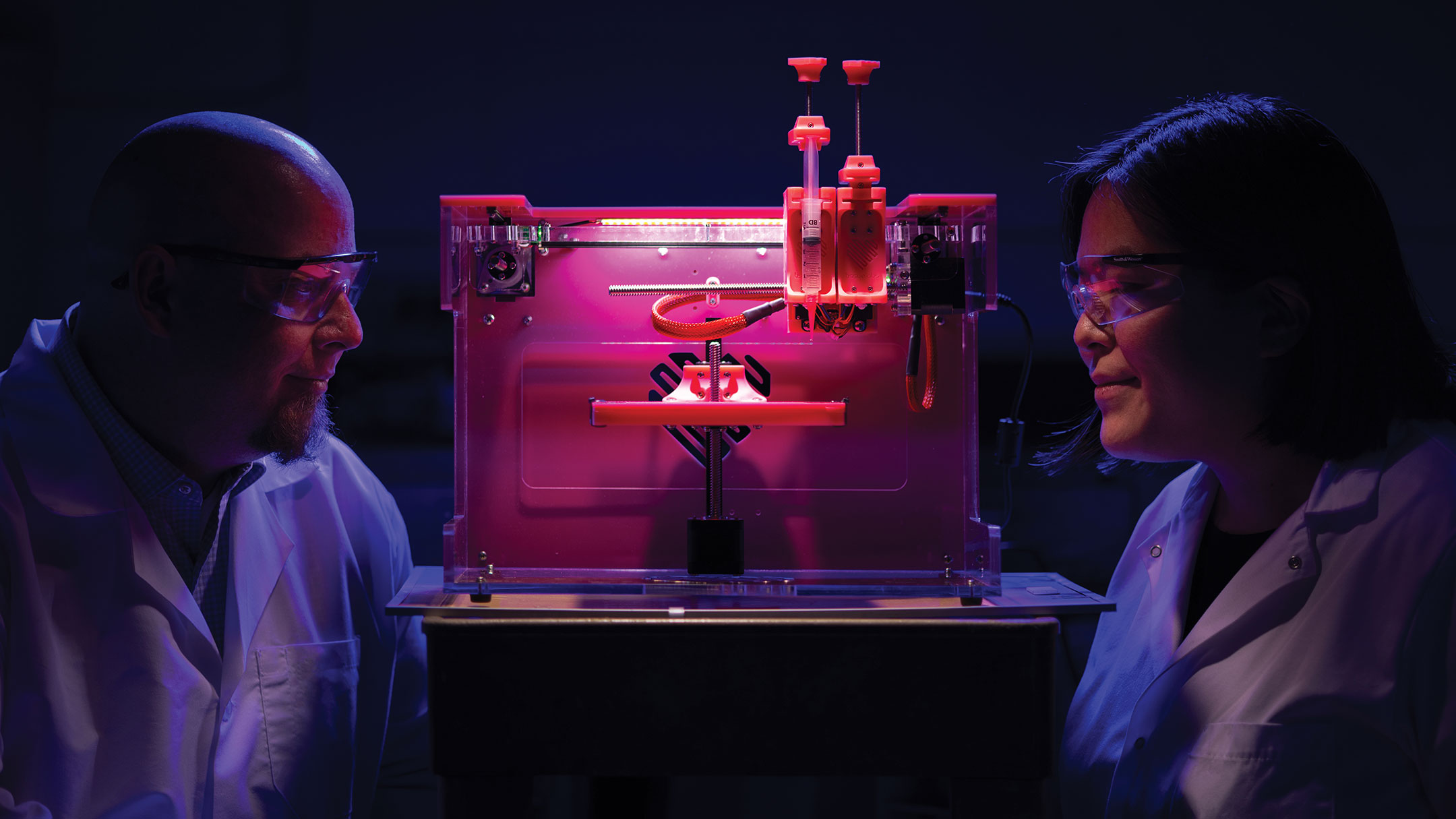 Roy Sturgill and Kaoru Ikuma examine a speciman under the pink glow of a grow light.